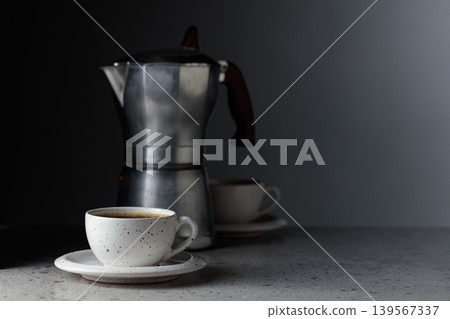 Cup of espresso and classic Italian aluminium moka pot on a gray stone table. 139567337