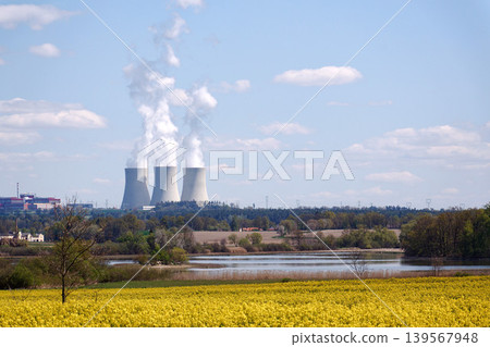 Cooling towers with steam on sky at nuclear power plant with pond and trees nature foreground, Temelin, Czech Republic, energy self-sufficiency, greenhouse emission reduction, global warming concept 139567948