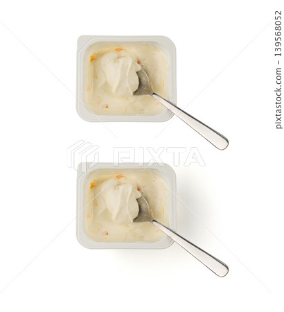 Yogurt cup isolated, yoghurt with orange fruits pieces in plastic pot, spoon in milk pudding Yogurt cup isolated, yoghurt with orange fruits pieces in plastic pot, spoon in milk pudding 139568052