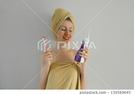 Happy young woman holding toothbrush and oral irrigator Happy young woman holding toothbrush and oral irrigator 139569045
