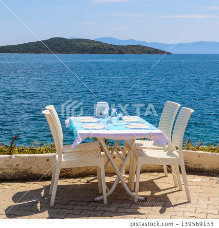 Outdoor restaurant table offering dining with a beautiful sea view in Bitez, Bodrum, Turkey Outdoor restaurant table offering dining with a beautiful sea view in Bitez, Bodrum, Turkey 139569133