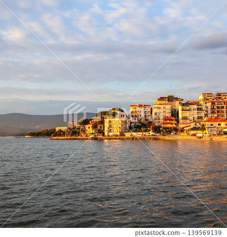 Gulluk, Milas, Turkey, coastal town buildings illuminated by golden hour light reflecting on the calm Aegean sea Gulluk, Milas, Turkey, coastal town buildings illuminated by golden hour light reflecting on the calm Aegean sea 139569139