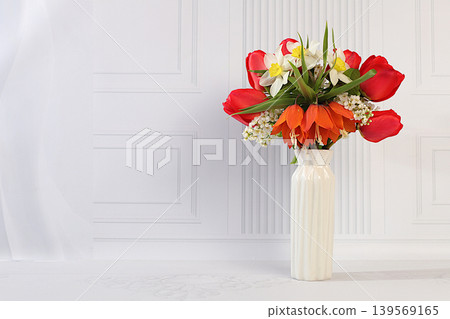 Still life with beautiful spring branches of blooming bird cherry, tulips, daffodils, and a fritillary in a vase against an elegant background. Abstract floral arrangement Still life with beautiful spring branches of blooming bird cherry, tulips, daffodils, and a fritillary in a vase against an elegant background. Abstract floral arrangement 139569165