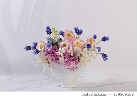 Still life with beautiful spring blooms of hyacinths, muscari, daisies, and forget me nots in a vase against an elegant background. Abstract floral composition and banner for the screen Still life with beautiful spring blooms of hyacinths, muscari, daisies, and forget me nots in a vase against an elegant background. Abstract floral composition and banner for the screen 139569168