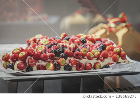Homemade Berry cake with strawberries, raspberries, blackberries, cream, jam rests on tray in bakery display. Cake dessert fits pastry shop, catering, celebration, menu, food advertising Homemade Berry cake with strawberries, raspberries, blackberries, cream, jam rests on tray in bakery display. Cake dessert fits pastry shop, catering, celebration, menu, food advertising 139569275