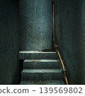 Narrow concrete staircase with exposed pipe and valve. worn steps and conduit run along damp wall, grime and rust accentuating industrial texture. intimate 139569802