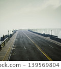 Curved roadway with strong leading lines guiding eye toward arches and horizon, stark lamppost rhythm and textured surface create graphic architectural study 139569804
