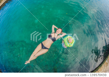 Mother and little son swimming together in a Mexican cenote with crystal clear water. Family travel, childhood adventure and tropical wellness lifestyle concept Mother and little son swimming together in a Mexican cenote with crystal clear water. Family travel, childhood adventure and tropical wellness lifestyle concept 139570430