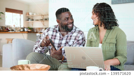 Discussing tablet, man in plaid shirt pointing, woman in green overshirt typing on laptop at home Discussing tablet, man in plaid shirt pointing, woman in green overshirt typing on laptop at home 139571620