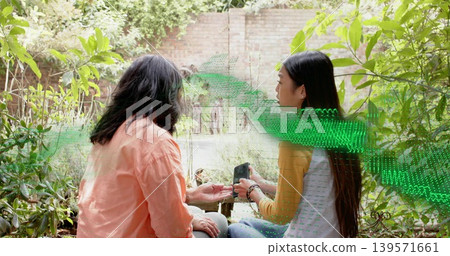 Holding smartphone women in peach shirt and gray top mustard sleeves checking palm near faucet yard Holding smartphone women in peach shirt and gray top mustard sleeves checking palm near faucet yard 139571661