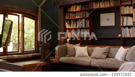 Displaying large leather sofa occupying center in reading room, bookshelves, throw pillows, stove Displaying large leather sofa occupying center in reading room, bookshelves, throw pillows, stove 139571681