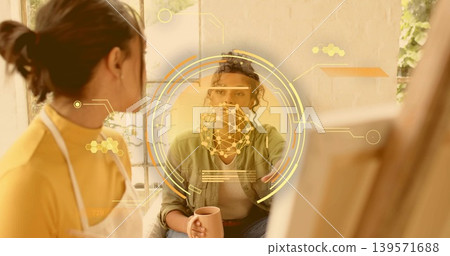 Holding mug, woman in green talking at studio with artist in white apron and AR overlay Holding mug, woman in green talking at studio with artist in white apron and AR overlay 139571688