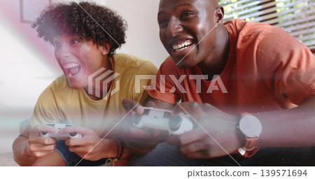 Playing two men leaning on couch at home, holding white gamepads, wearing mustard and orange shirts Playing two men leaning on couch at home, holding white gamepads, wearing mustard and orange shirts 139571694