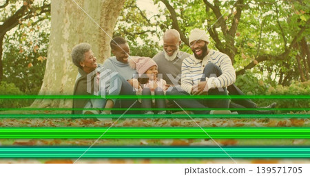 Sitting family wearing sweaters on leafy ground by tree trunk, showing green scan lines Sitting family wearing sweaters on leafy ground by tree trunk, showing green scan lines 139571705