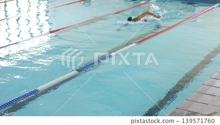 Swimming woman freestyling at aquatic pool, lane dividers, in one-piece, cap, goggles, copy space Swimming woman freestyling at aquatic pool, lane dividers, in one-piece, cap, goggles, copy space 139571760