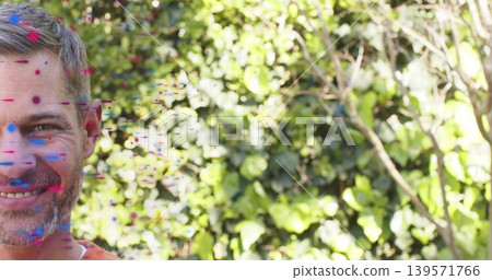 Smiling mature man posing in garden with paint splashes, dense ivy hedge, orange shirt, copy space Smiling mature man posing in garden with paint splashes, dense ivy hedge, orange shirt, copy space 139571766