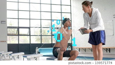 Sitting swimmer wearing swim cap, jammers, listening to coach in white hoodie at blocks, tablet HUD Sitting swimmer wearing swim cap, jammers, listening to coach in white hoodie at blocks, tablet HUD 139571774