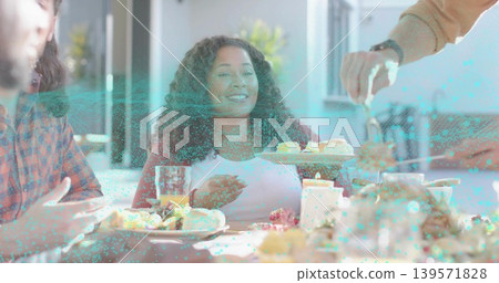 Smiling woman receiving pastry from serving tray while holding glass of juice at dining table 139571828