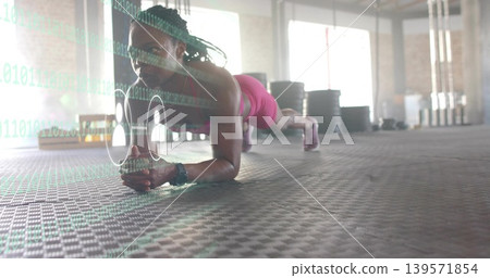 Exercising woman doing forearm plank on rubber mat in gym, wearing pink top and watch, overlay Exercising woman doing forearm plank on rubber mat in gym, wearing pink top and watch, overlay 139571854