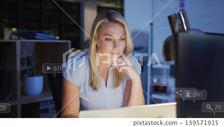 Working mature woman in light blue blouse using laptop at office, showing UI overlays Working mature woman in light blue blouse using laptop at office, showing UI overlays 139571915
