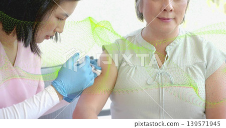 Giving nurse vaccinating Asian woman in clinic with syringe, nitrile gloves, scrubs, green overlay Giving nurse vaccinating Asian woman in clinic with syringe, nitrile gloves, scrubs, green overlay 139571945