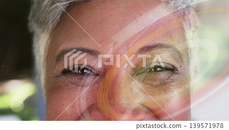 Showing mature woman with gray hair smiling in interior room with colorful swirl and bokeh Showing mature woman with gray hair smiling in interior room with colorful swirl and bokeh 139571978