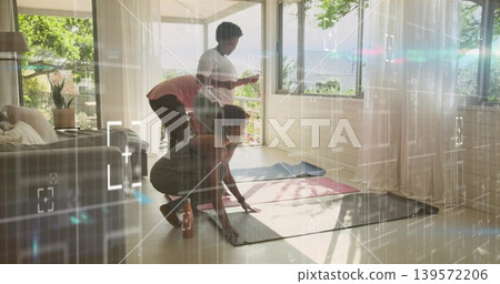 Crouching woman in gray-tank dark-leggings arranging mat in living room, three mats, water bottle Crouching woman in gray-tank dark-leggings arranging mat in living room, three mats, water bottle 139572206
