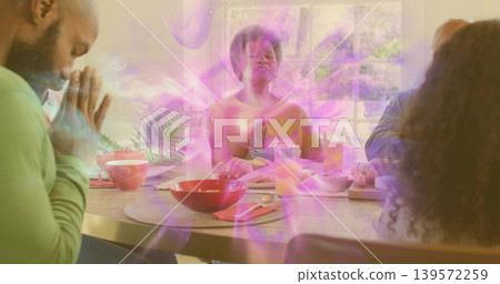 Praying woman wearing mustard sweater leading prayer at home dining table, with red bowls Praying woman wearing mustard sweater leading prayer at home dining table, with red bowls 139572259