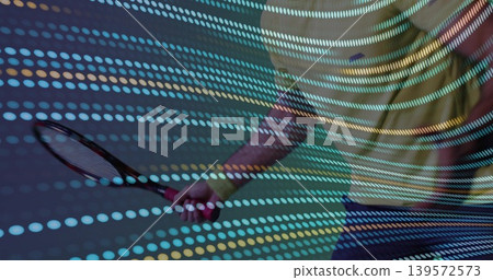 Holding tennis racket, male torso wearing yellow tee and dark shorts in studio with dotted lights Holding tennis racket, male torso wearing yellow tee and dark shorts in studio with dotted lights 139572573