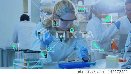 Pipetting scientist moving liquid into microtube rack at bench with lab coat, goggles, blue gloves Pipetting scientist moving liquid into microtube rack at bench with lab coat, goggles, blue gloves 139572591