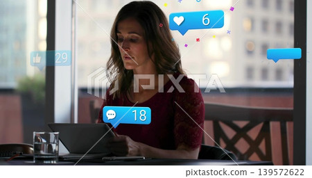Reading woman holding tablet at city window table in burgundy lace top, notifications floating Reading woman holding tablet at city window table in burgundy lace top, notifications floating 139572622