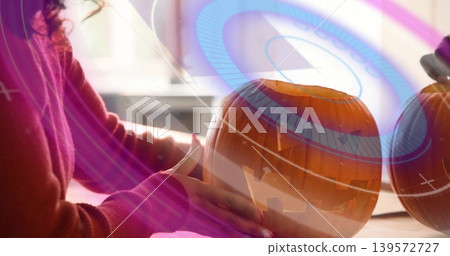 Working woman in rust knit sweater carving jack-o'-lantern on kitchen table, with blue overlays Working woman in rust knit sweater carving jack-o'-lantern on kitchen table, with blue overlays 139572727