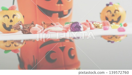 Lining row of Halloween candies and pumpkin containers on glossy studio tabletop, reflecting Lining row of Halloween candies and pumpkin containers on glossy studio tabletop, reflecting 139572760