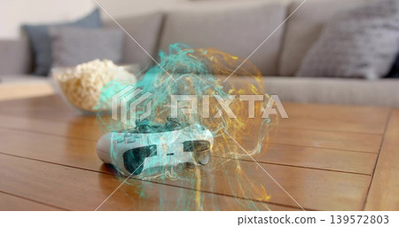 Glowing white wireless game controller releasing teal and amber smoke above coffee table, popcorn Glowing white wireless game controller releasing teal and amber smoke above coffee table, popcorn 139572803