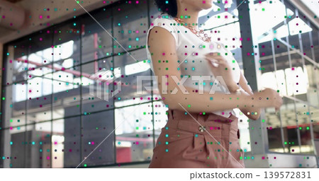 Standing woman adjusting chain necklace in studio by windows, white ribbed top, pink pants, dots Standing woman adjusting chain necklace in studio by windows, white ribbed top, pink pants, dots 139572831