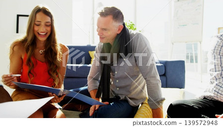 Smiling woman in red sleeveless top holding blue binder and pen in office lounge, copy space Smiling woman in red sleeveless top holding blue binder and pen in office lounge, copy space 139572948