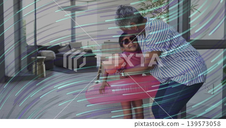 Hugging woman adjusting child wearing pink swimsuit and sunglasses in swim ring at home, copy space Hugging woman adjusting child wearing pink swimsuit and sunglasses in swim ring at home, copy space 139573058
