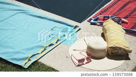 Resting straw hat with pink sunglasses occupying right poolside, snorkel, yellow towel, blue bottle Resting straw hat with pink sunglasses occupying right poolside, snorkel, yellow towel, blue bottle 139573086
