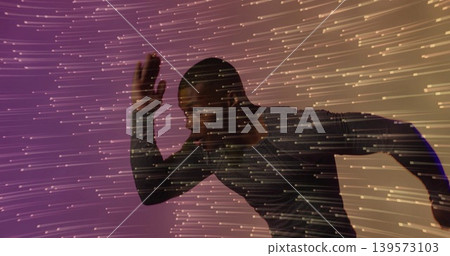 Sprinting adult male leaning forward in studio, wearing fitted athletic top with projected streaks Sprinting adult male leaning forward in studio, wearing fitted athletic top with projected streaks 139573103