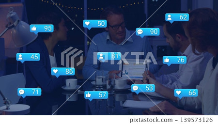 Analyzing team in suits reviewing tablet charts in boardroom at night, with social icons, coffee Analyzing team in suits reviewing tablet charts in boardroom at night, with social icons, coffee 139573126