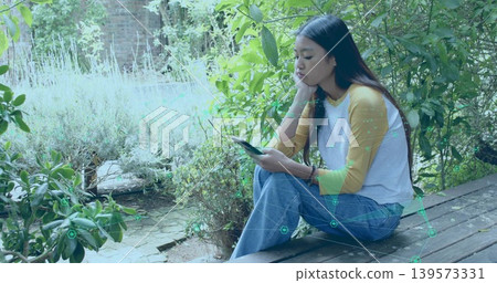 Sitting Asian woman holding smartphone, resting on deck mustard raglan AR overlay, copy space 139573331