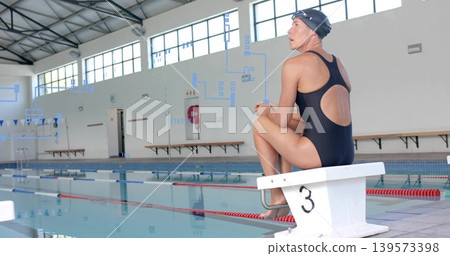 Waiting female swimmer sitting on block 3 at pool, wearing black swimsuit, cap, goggles, copy space Waiting female swimmer sitting on block 3 at pool, wearing black swimsuit, cap, goggles, copy space 139573398