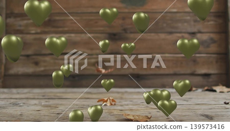 Floating olive-green heart-shaped metallic balloons with plank wall, wooden floor, dry leaves Floating olive-green heart-shaped metallic balloons with plank wall, wooden floor, dry leaves 139573416