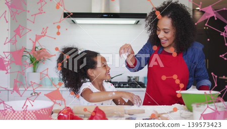 Sprinkling woman in red apron guiding daughter in home kitchen, with rolling pin and green bowl Sprinkling woman in red apron guiding daughter in home kitchen, with rolling pin and green bowl 139573423