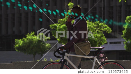 Talking on phone, commuter standing at plaza, wearing blazer, holding white bike with coiled lock Talking on phone, commuter standing at plaza, wearing blazer, holding white bike with coiled lock 139573435