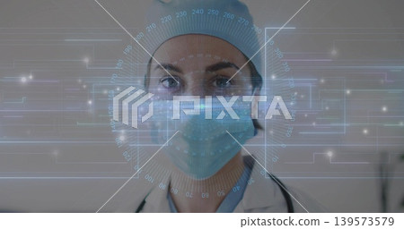 Facing female doctor wearing surgical cap, surgical mask and stethoscope in clinic, with AR HUD Facing female doctor wearing surgical cap, surgical mask and stethoscope in clinic, with AR HUD 139573579