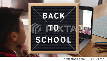 Showing letter board reading BACK TO SCHOOL home table, child in plaid shirt using laptop pencils Showing letter board reading BACK TO SCHOOL home table, child in plaid shirt using laptop pencils 139573754