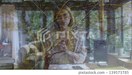 Writing Chinese woman wearing cardigan over blouse at home desk with papers overlaid branches Writing Chinese woman wearing cardigan over blouse at home desk with papers overlaid branches 139573785