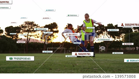 Playing players in neon vests sliding, controlling ball on school field at sunset with ID labels Playing players in neon vests sliding, controlling ball on school field at sunset with ID labels 139573808