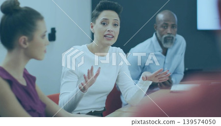 Speaking mature adult woman wearing white top gesturing at office meeting table, with laptop Speaking mature adult woman wearing white top gesturing at office meeting table, with laptop 139574050